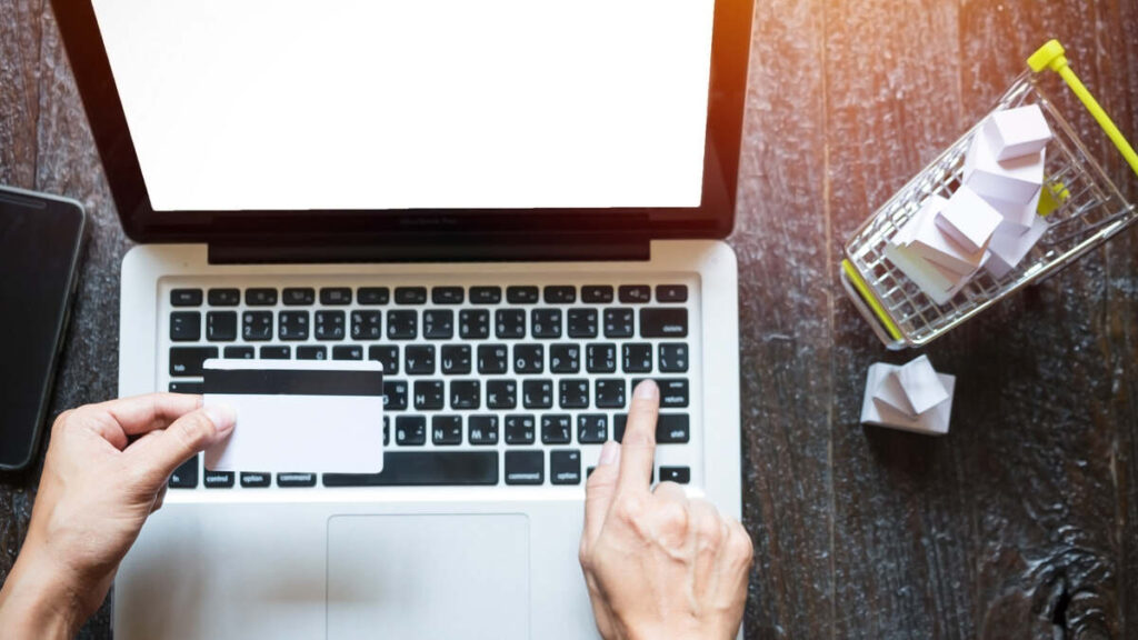 Laptop, kreditna kartica i mala korpa za kupovinu na radnom stolu